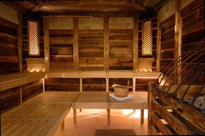 A wooden cabin interior with a bench, a table, and a bucket. - Parkhotel Maximilian Ottobeuren Resort&Spa (Ottobeuren)
