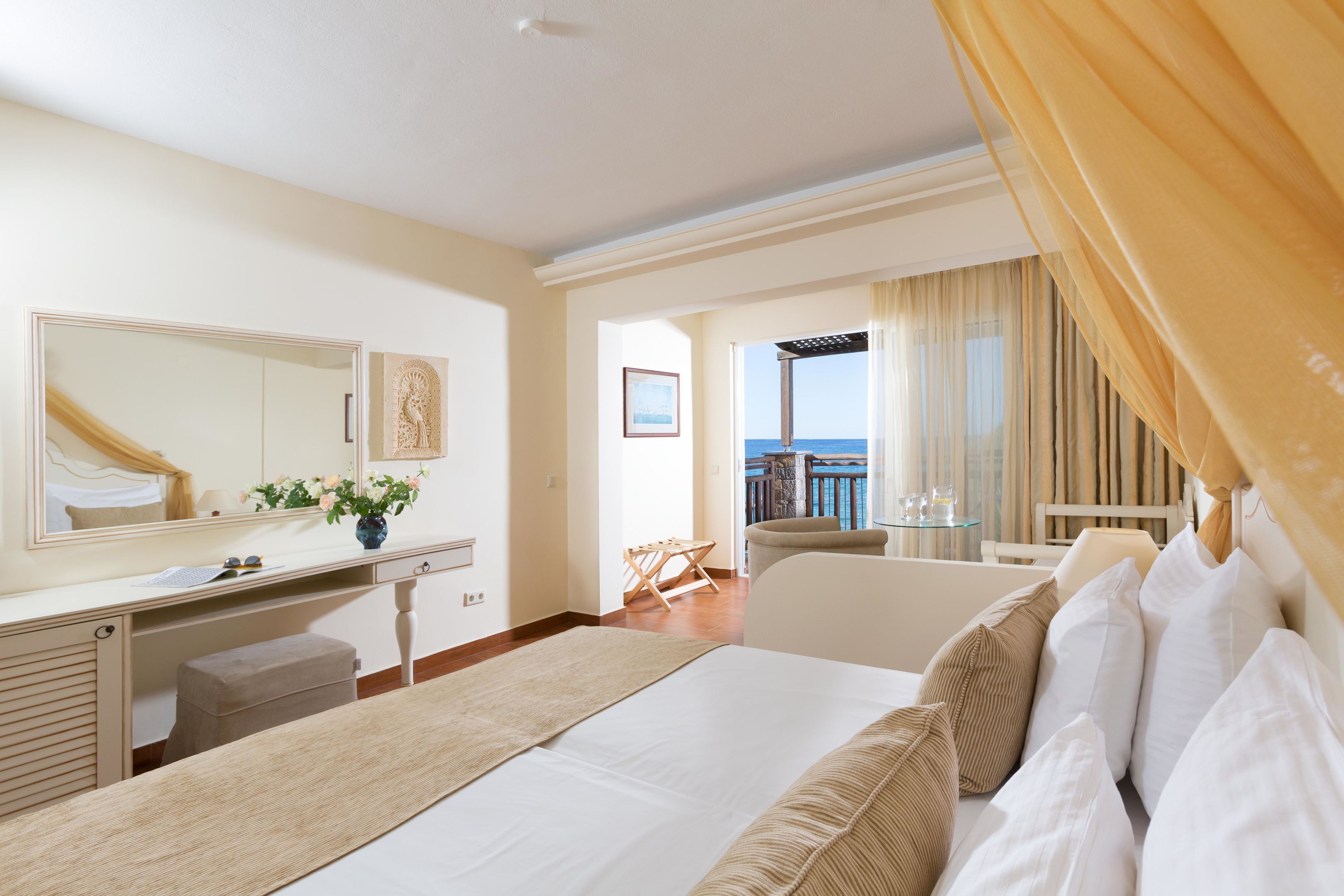 A hotel room with a bed, a desk, a chair, and a balcony with a view.