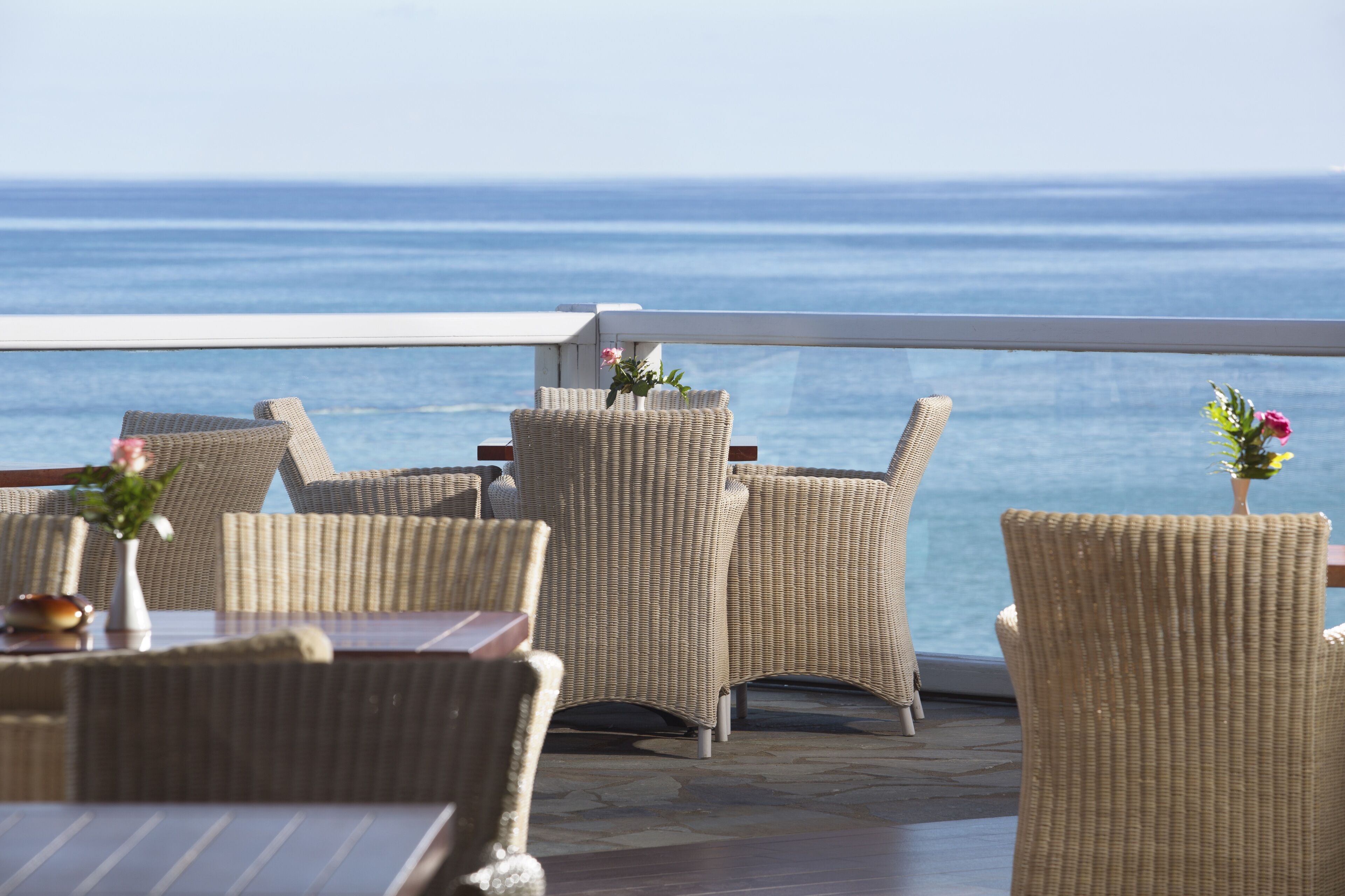 Una terraza con mobiliario de mimbre y vista al océano.
