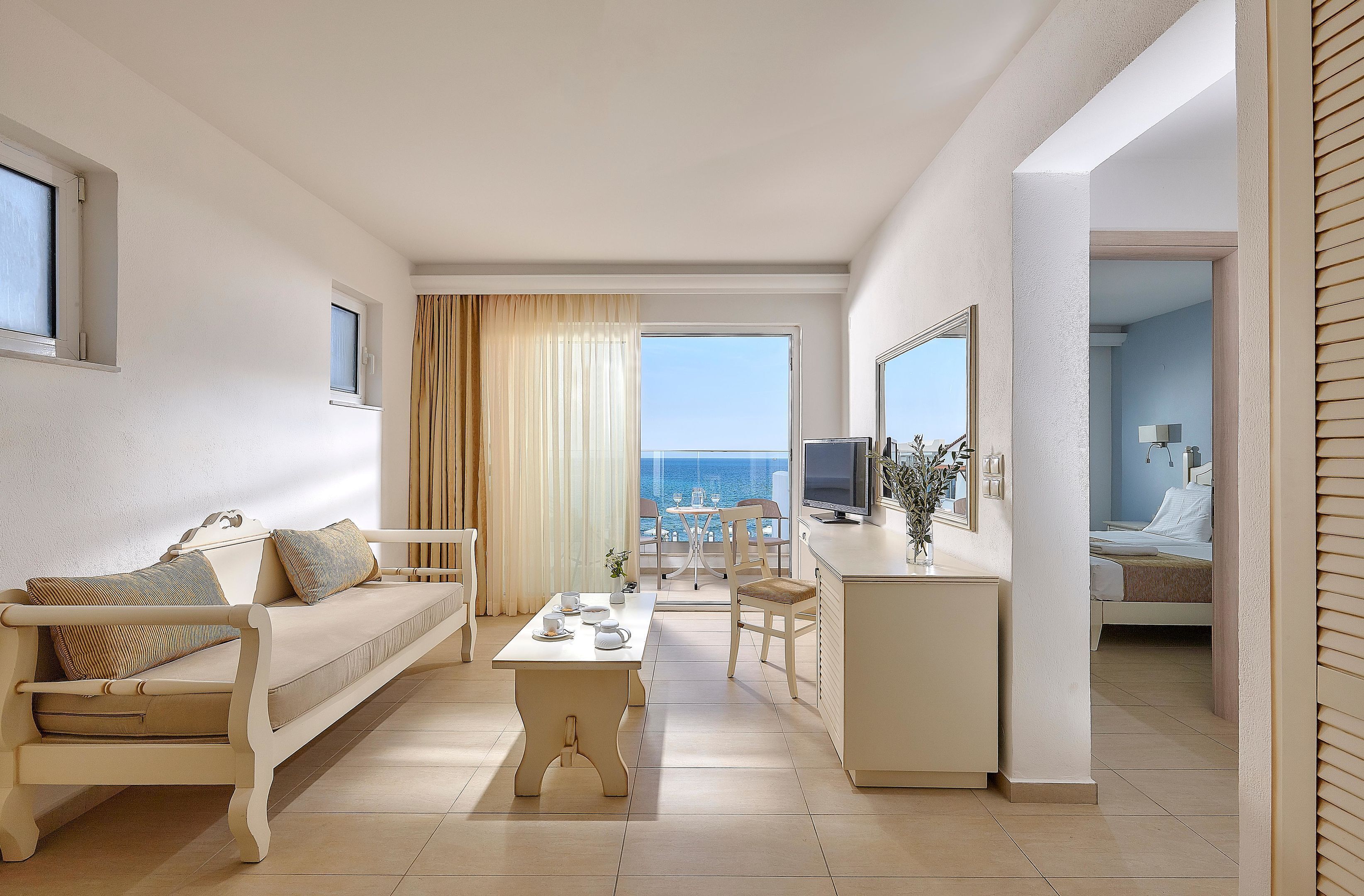 A modern living room with a sofa, coffee table, and a view of the sea.
