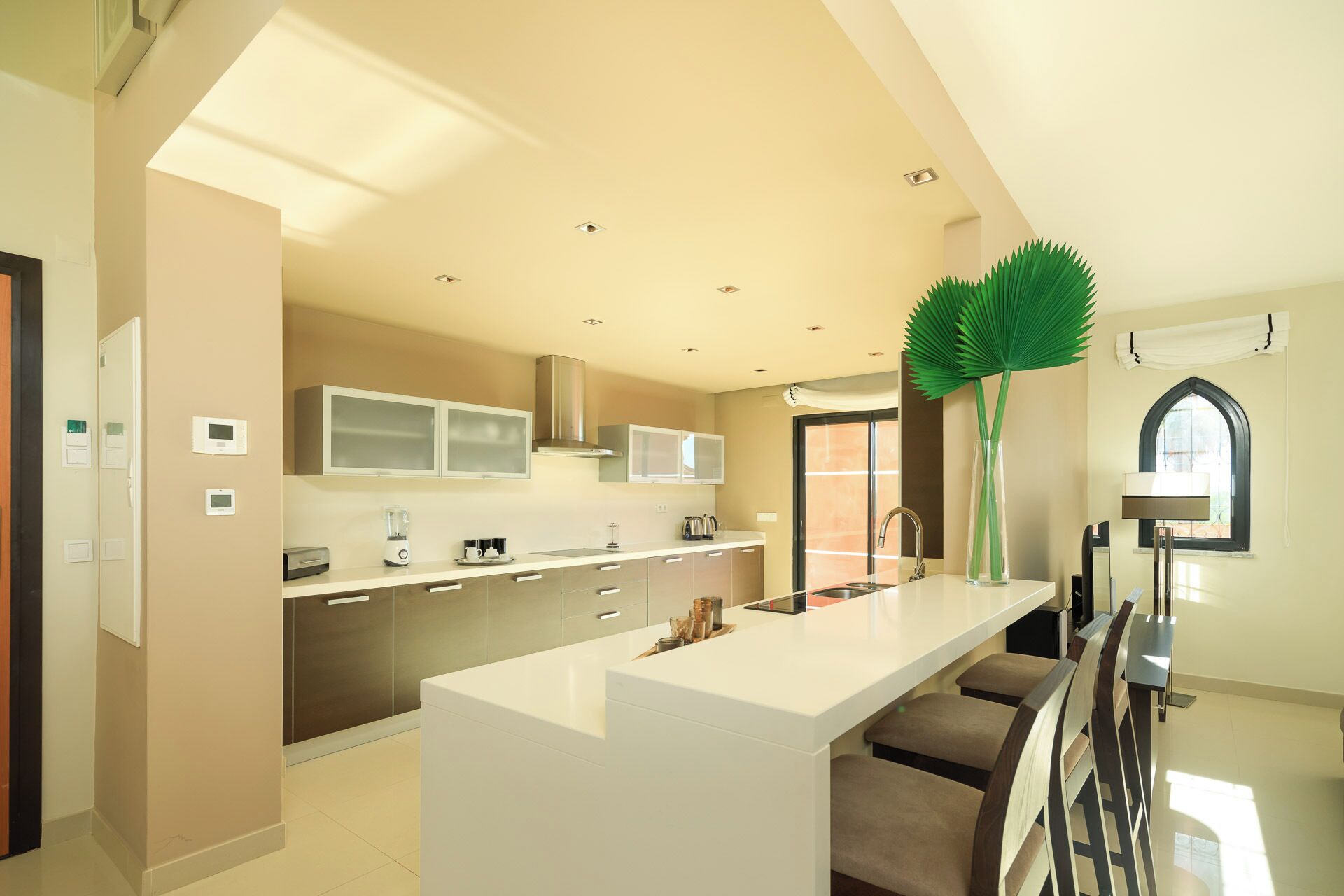 Een moderne keuken met een groot eiland, ingebouwde apparatuur en uitzicht op buiten.