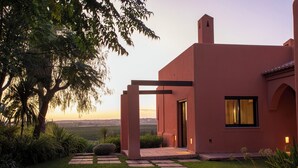 Une maison moderne dotée d’un patio, d’un grand arbre et offrant une vue sur la campagne.