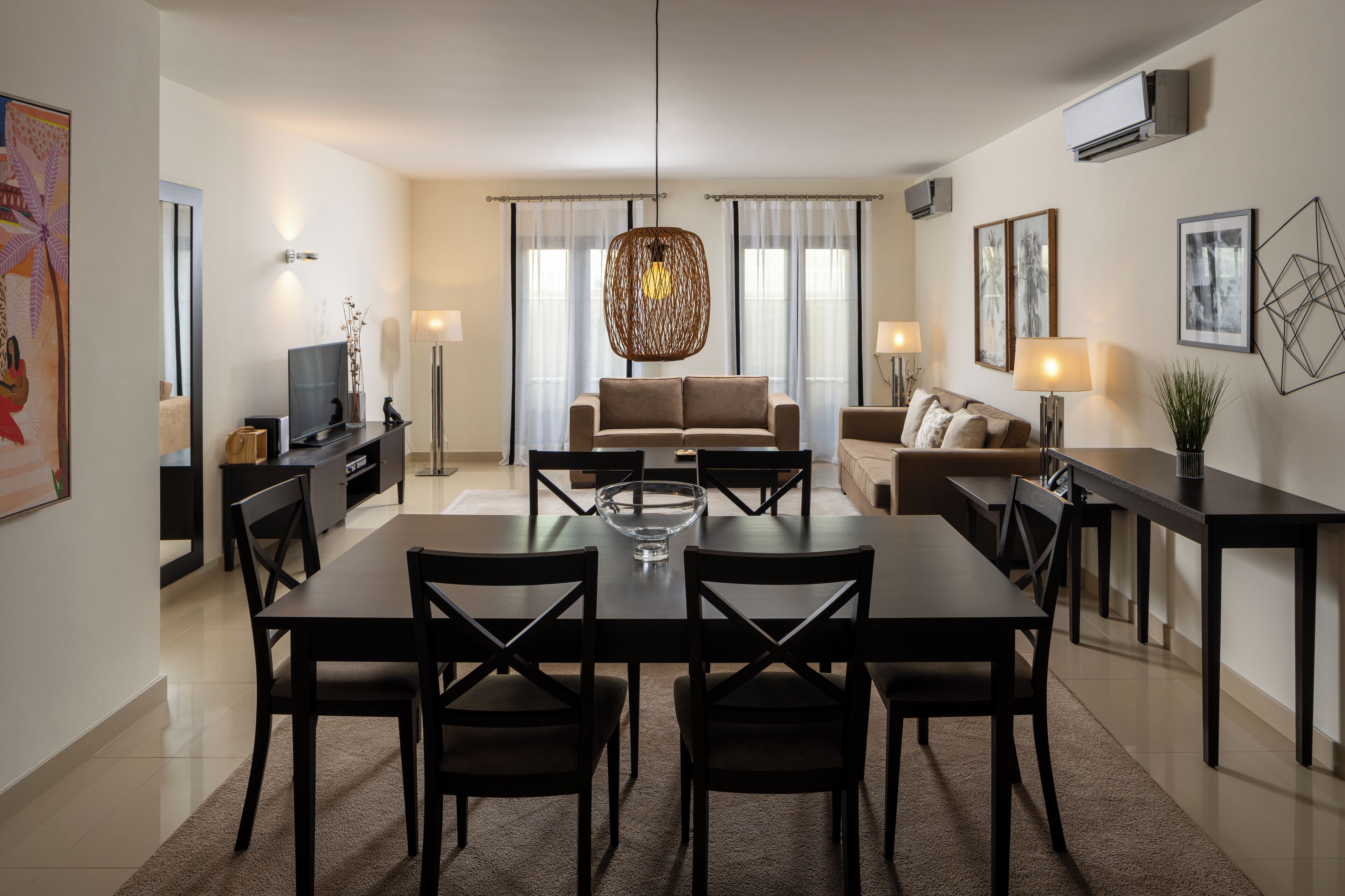 A modern living room with a dining area, featuring a sofa set, a coffee table, and a TV.