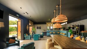 Un intérieur moderne avec une table à manger en bois, des chaises recouvertes d’un tissu vert et un coin bar.