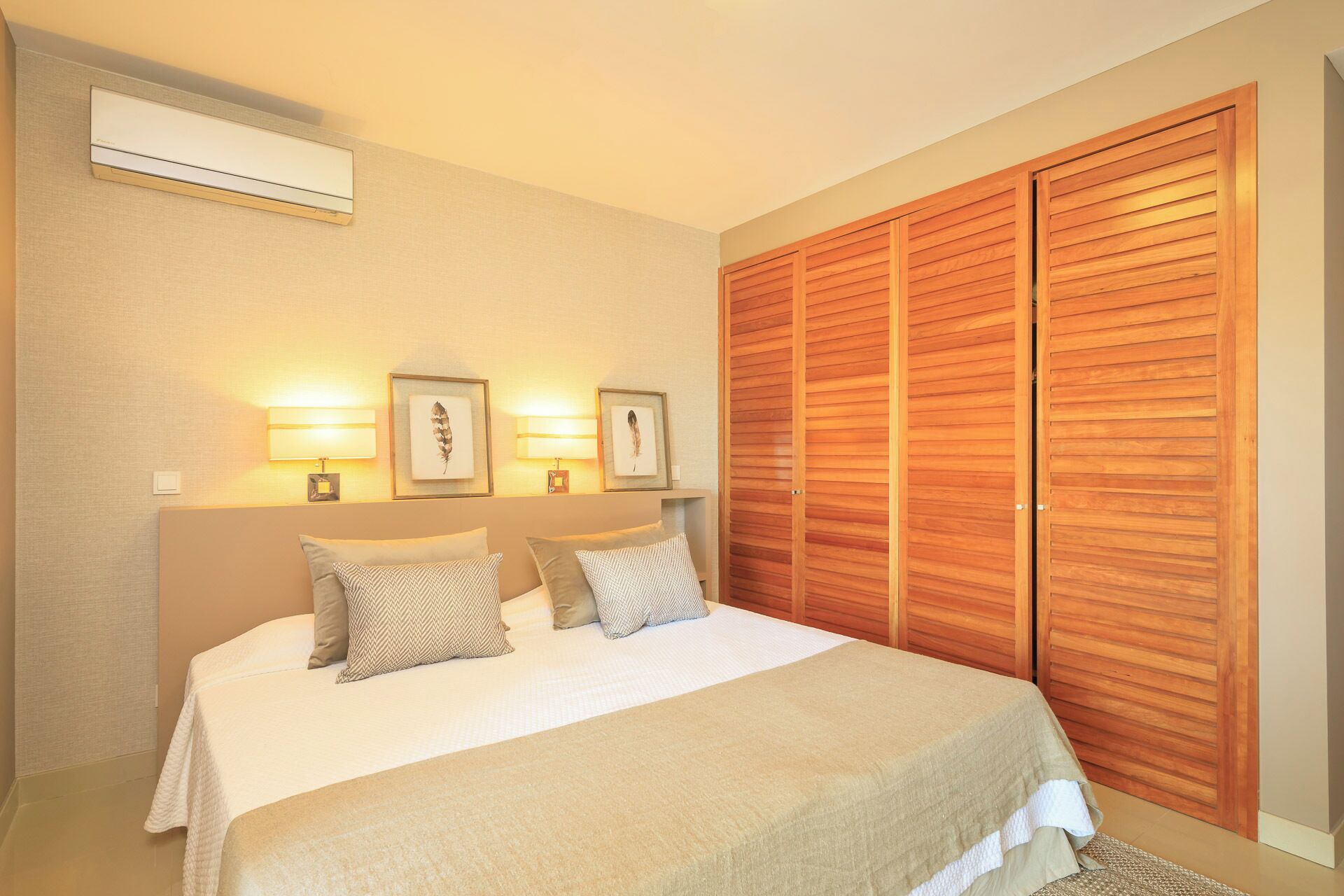 A bedroom with a bed, two wall-mounted lamps, and a wooden wardrobe.