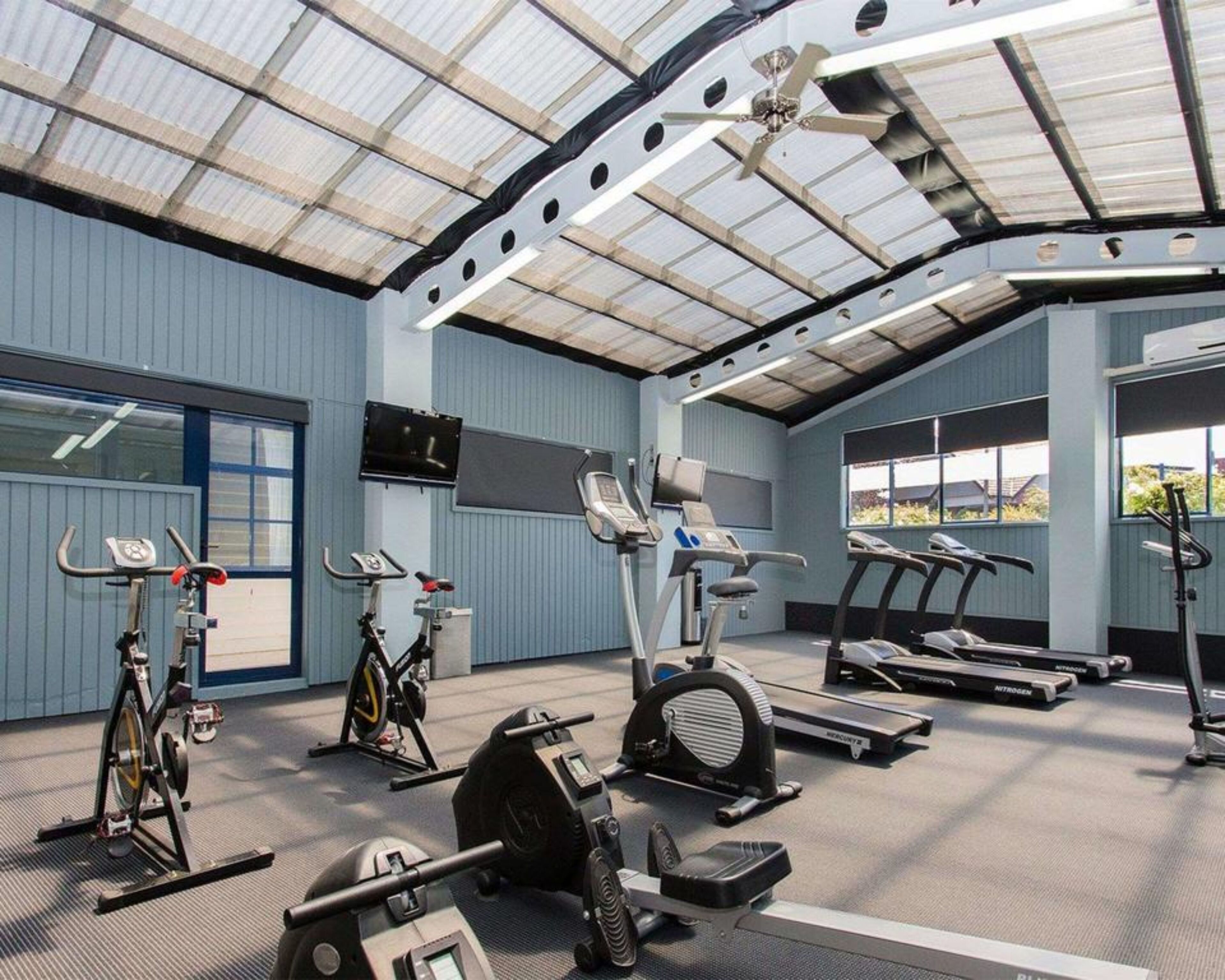 A gym with various exercise equipment, including treadmills, stationary bikes, and elliptical machines.