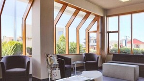 Un área de espera moderna con asientos cómodos, ventanas amplias y un mostrador de recepción.