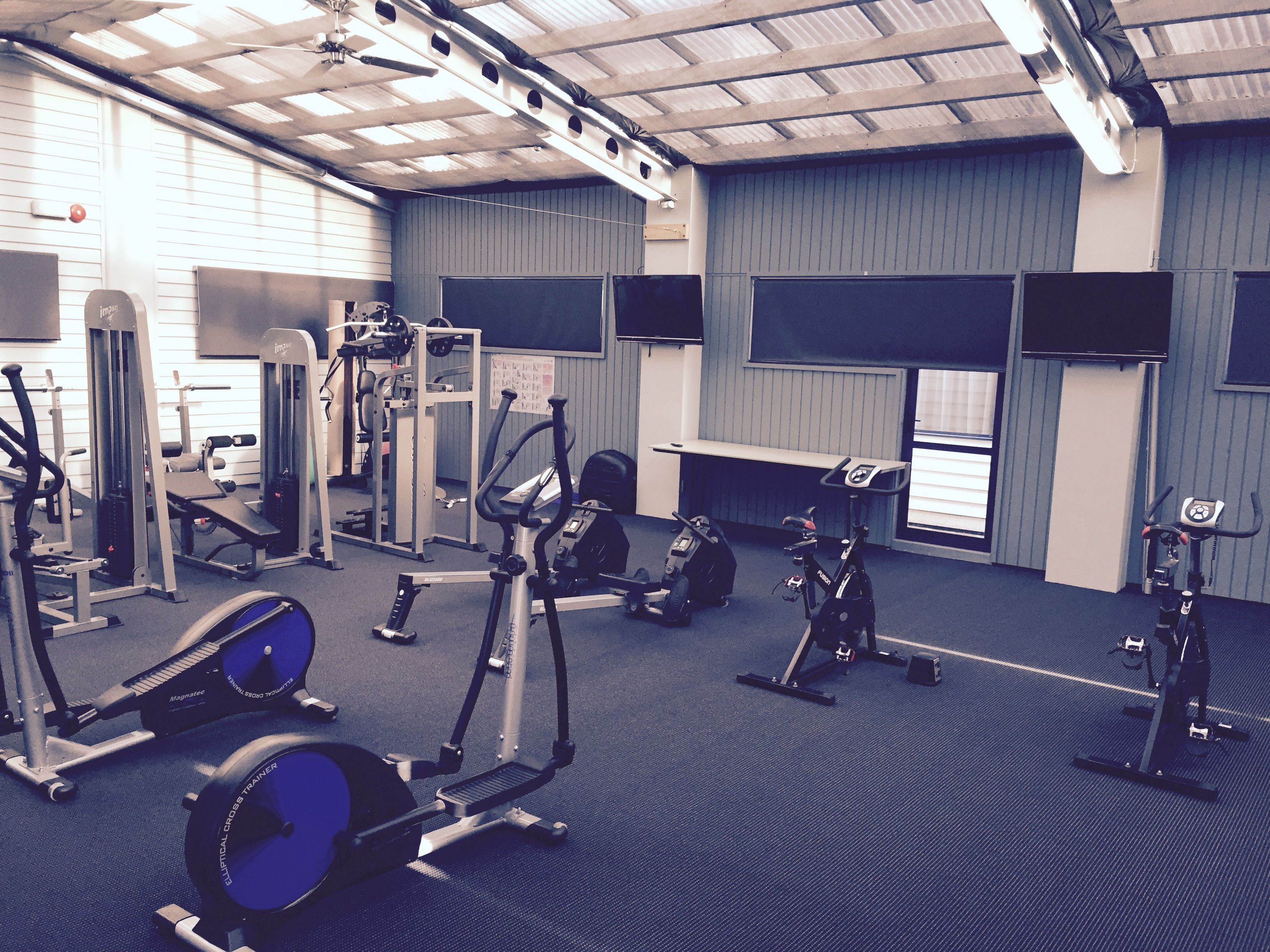 A gym with various exercise equipment, including treadmills, weight machines, and a stationary bike.