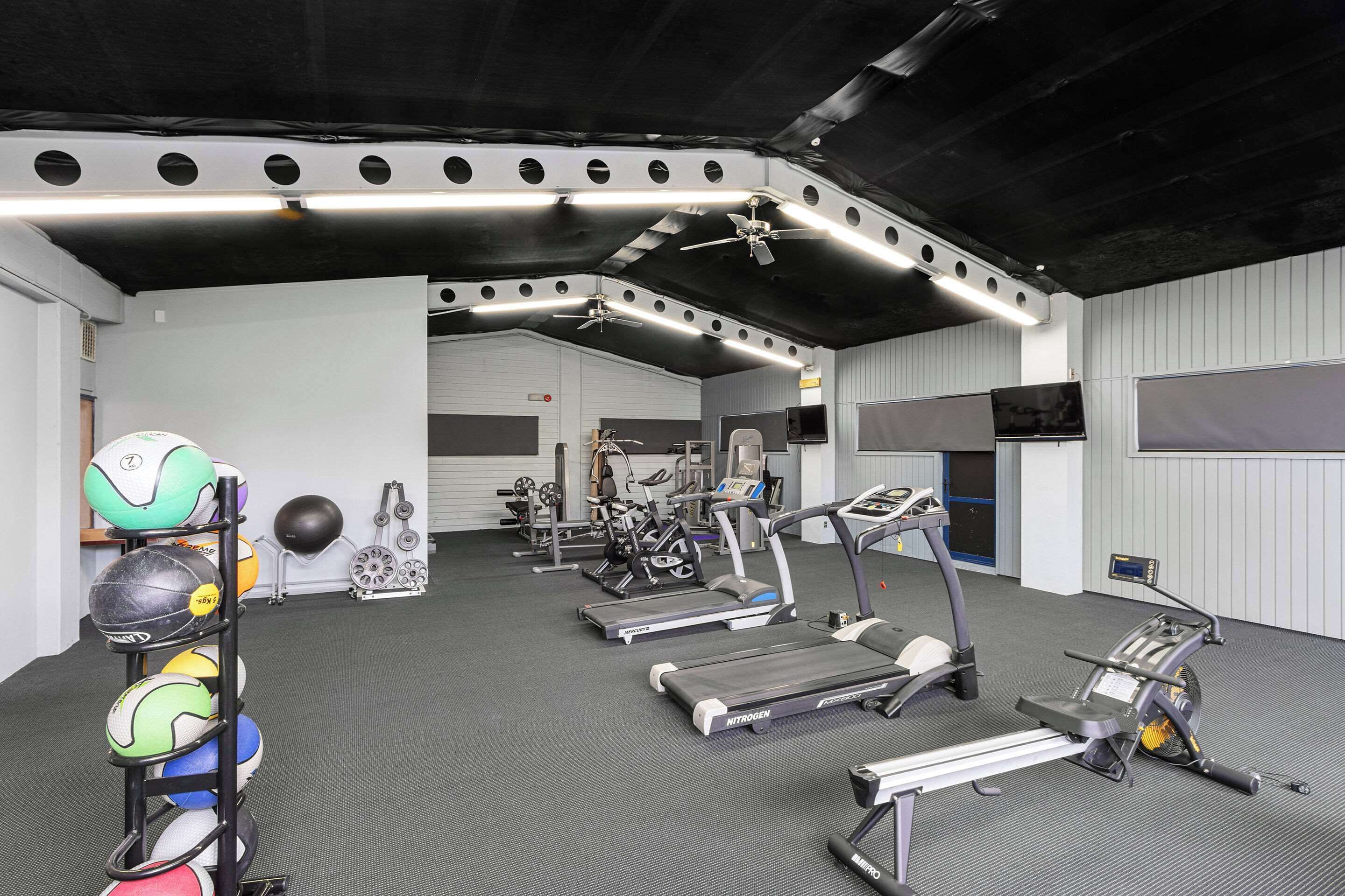 A gym with treadmills, stationary bikes, and a variety of exercise balls.