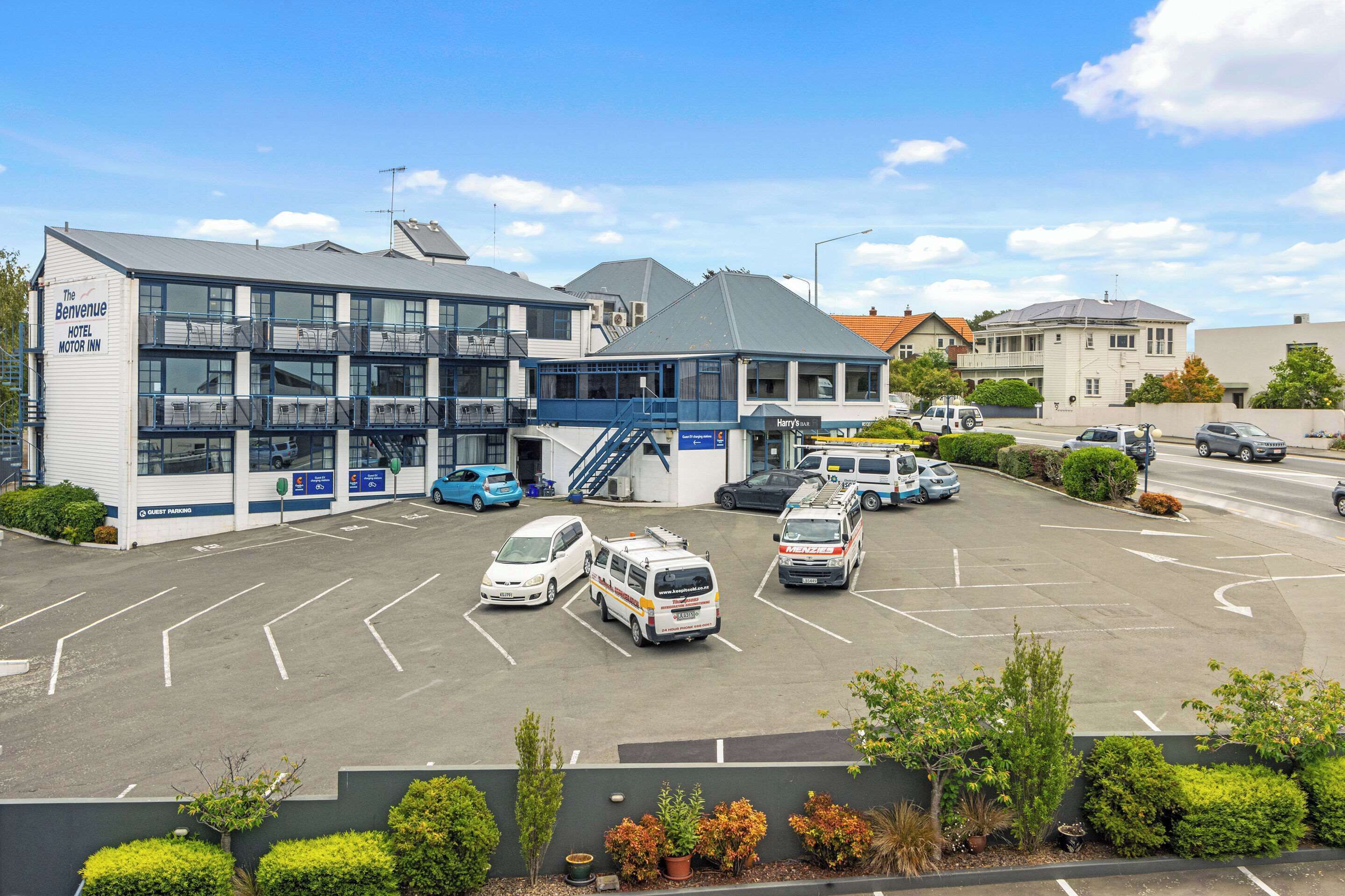 A hotel with a multi-story parking garage, several parked vehicles, and a clear sky.