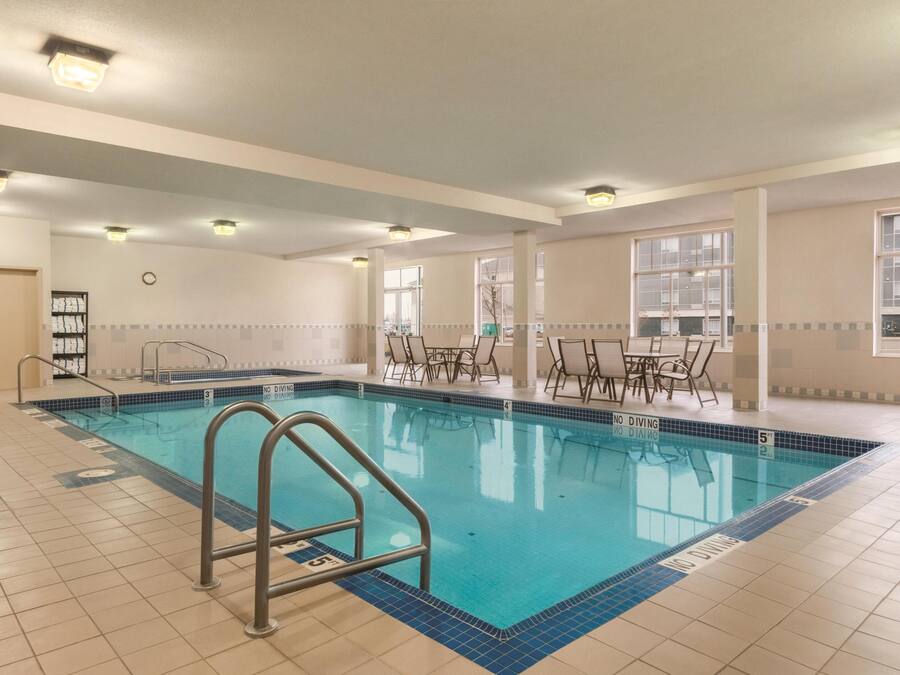 Una piscina interior con carriles claramente delimitados, zona de trampolín y mesas de comedor cercanas.