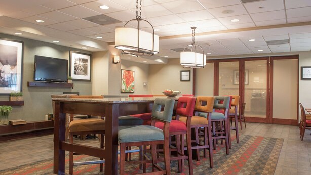 A hotel lobby with a bar area, seating, and a television screen.