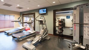 A hotel fitness center with treadmills, an elliptical, and a weight bench.