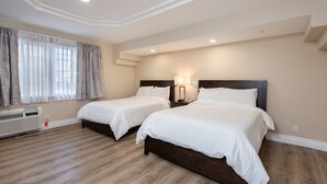 Habitación de hotel con dos camas, una mesita de noche con lámpara, una ventana con cortinas y un radiador.