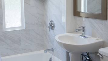 A modern bathroom with a bathtub, a sink, and a shower.