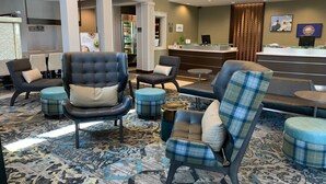 Een hotel lobby met zithoeken, een receptiebalie en een koelkast gevuld met drankjes.