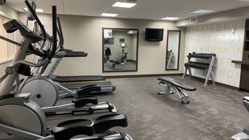 A gym with treadmills, a bench, and a mirror.