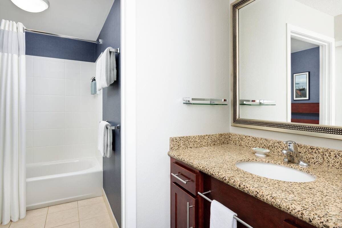 A bathroom with a bathtub, a sink, and a mirror.