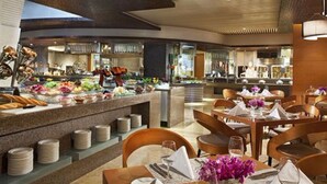 Un restaurante moderno con barra libre, mesas de madera y una cocina al fondo.