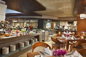 Un restaurante moderno con barra libre, mesas de madera y una cocina al fondo.