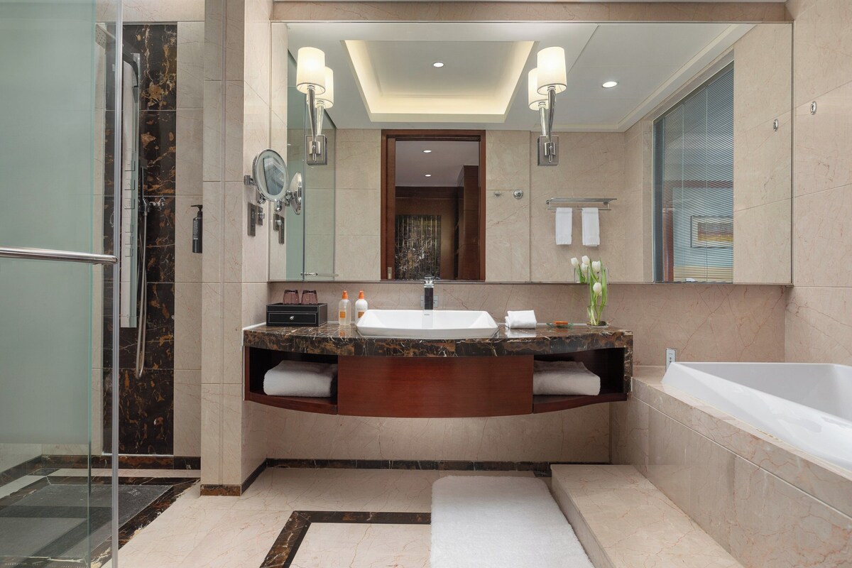 Un baño moderno con un espejo grande, un lavabo, una bañera y una zona de ducha.