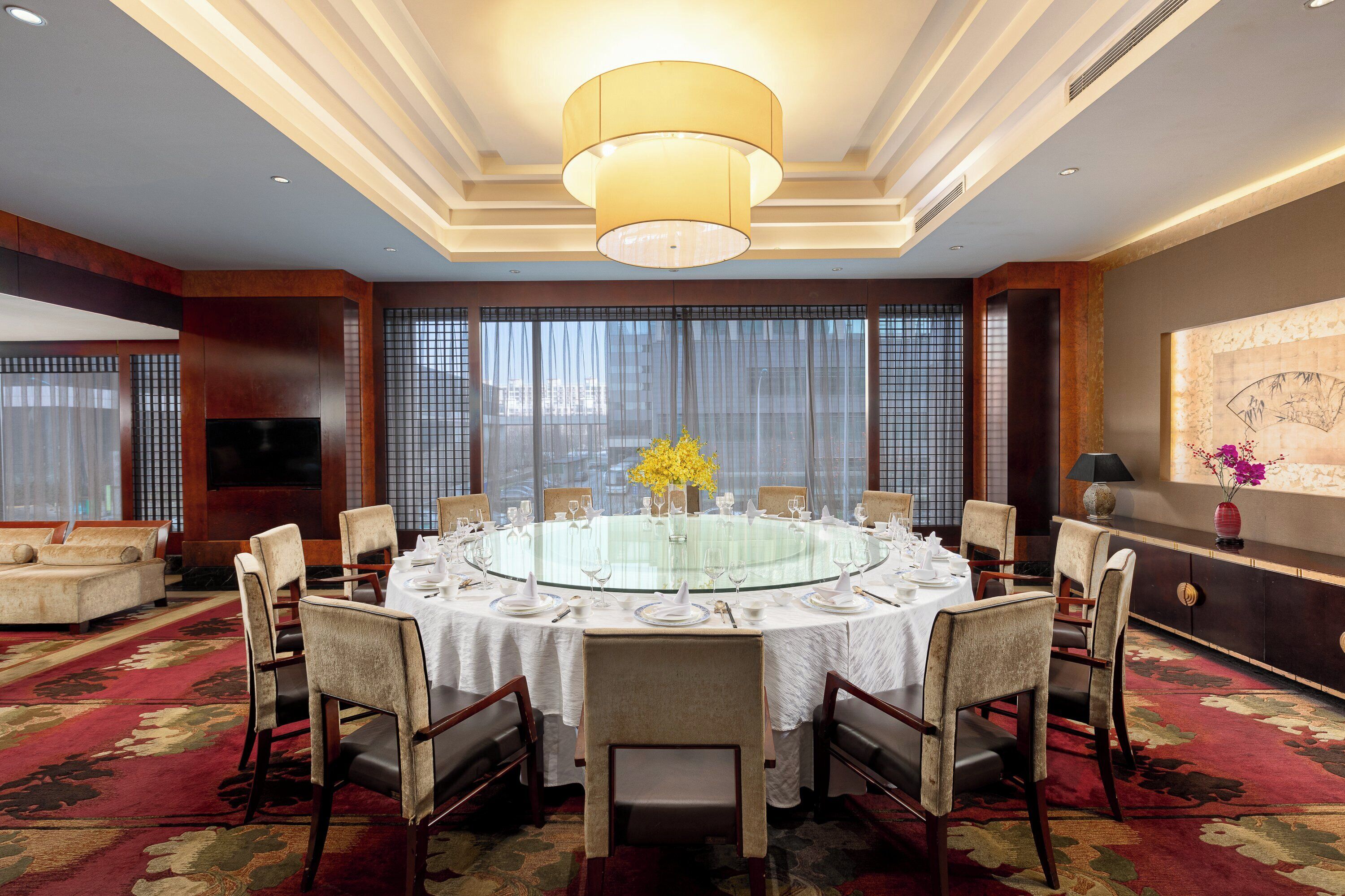 A conference room with a round table, chairs, and a chandelier.