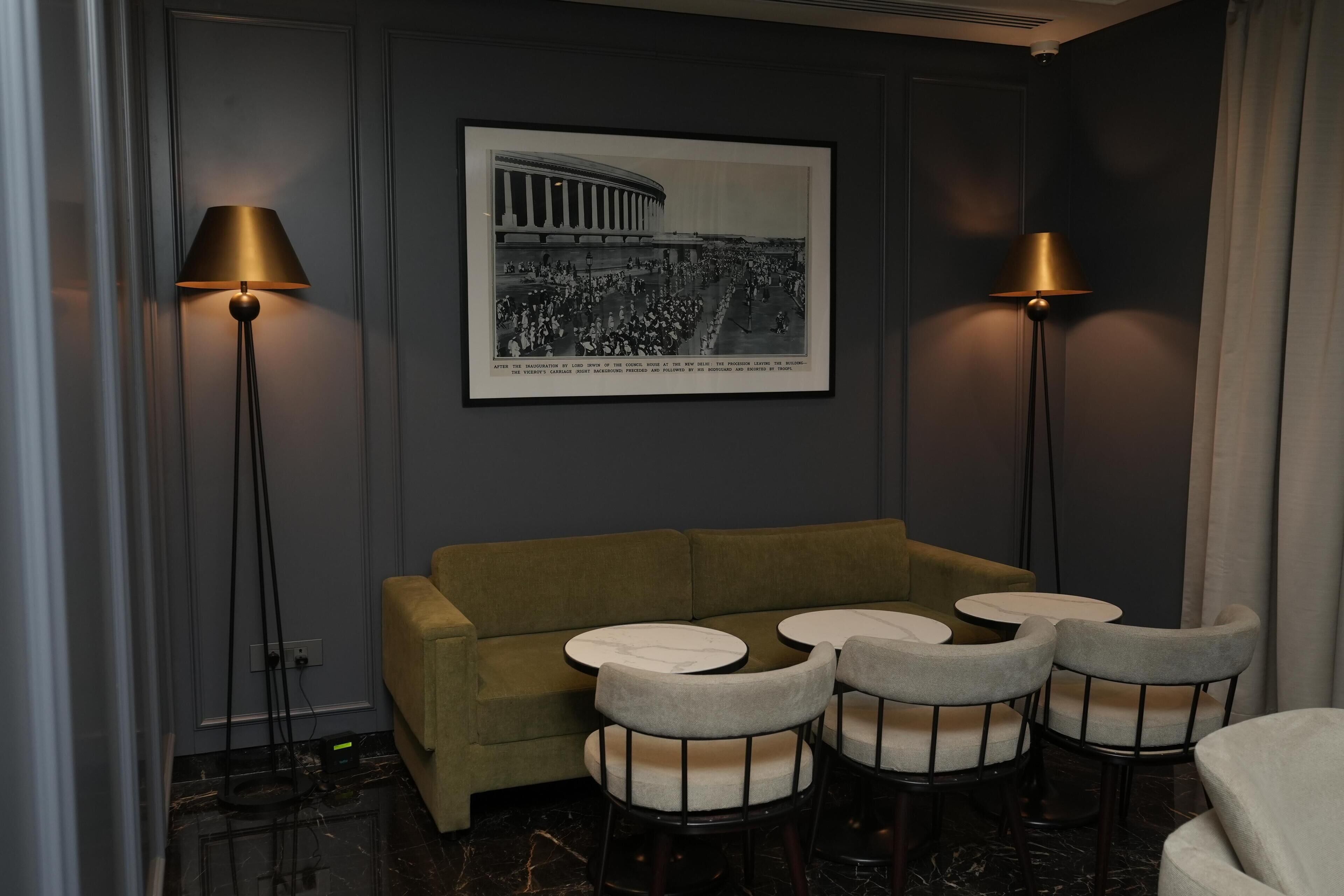 A room with a sofa, round tables, and two floor lamps.