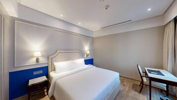 Ein Hotelzimmer mit einem großen Bett, Nachttischlampen, einem Schreibtisch und einem Sessel.