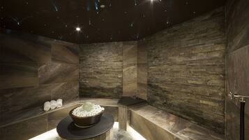Bathroom features a stone wall, black countertop, and a bench with a black seat.