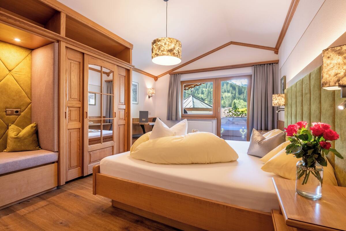 Un dormitorio con cama, armario de madera y ventana con vista a la vegetación.