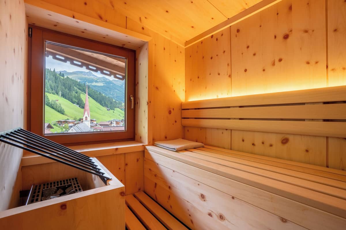 Una sauna de madera con ventana, bancos y un perchero para toallas.