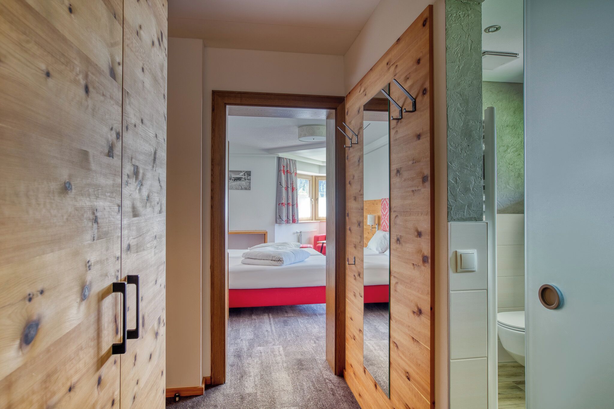 Ein Schlafzimmer mit einem Bett, einem Holzschrank und einem Badezimmer mit Toilette und Waschbecken.