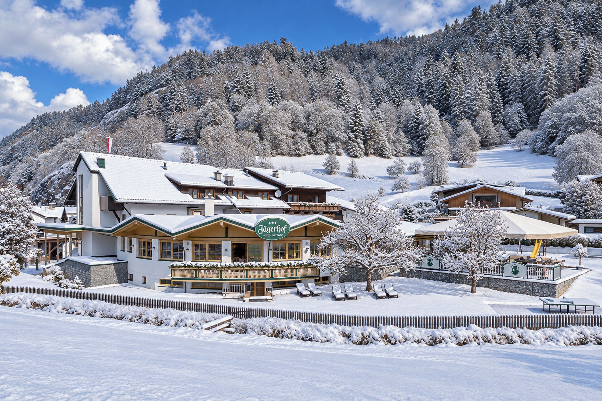 Ein Hotel mit verschneiter Landschaft, einer Skipiste und einem Berg im Hintergrund.
