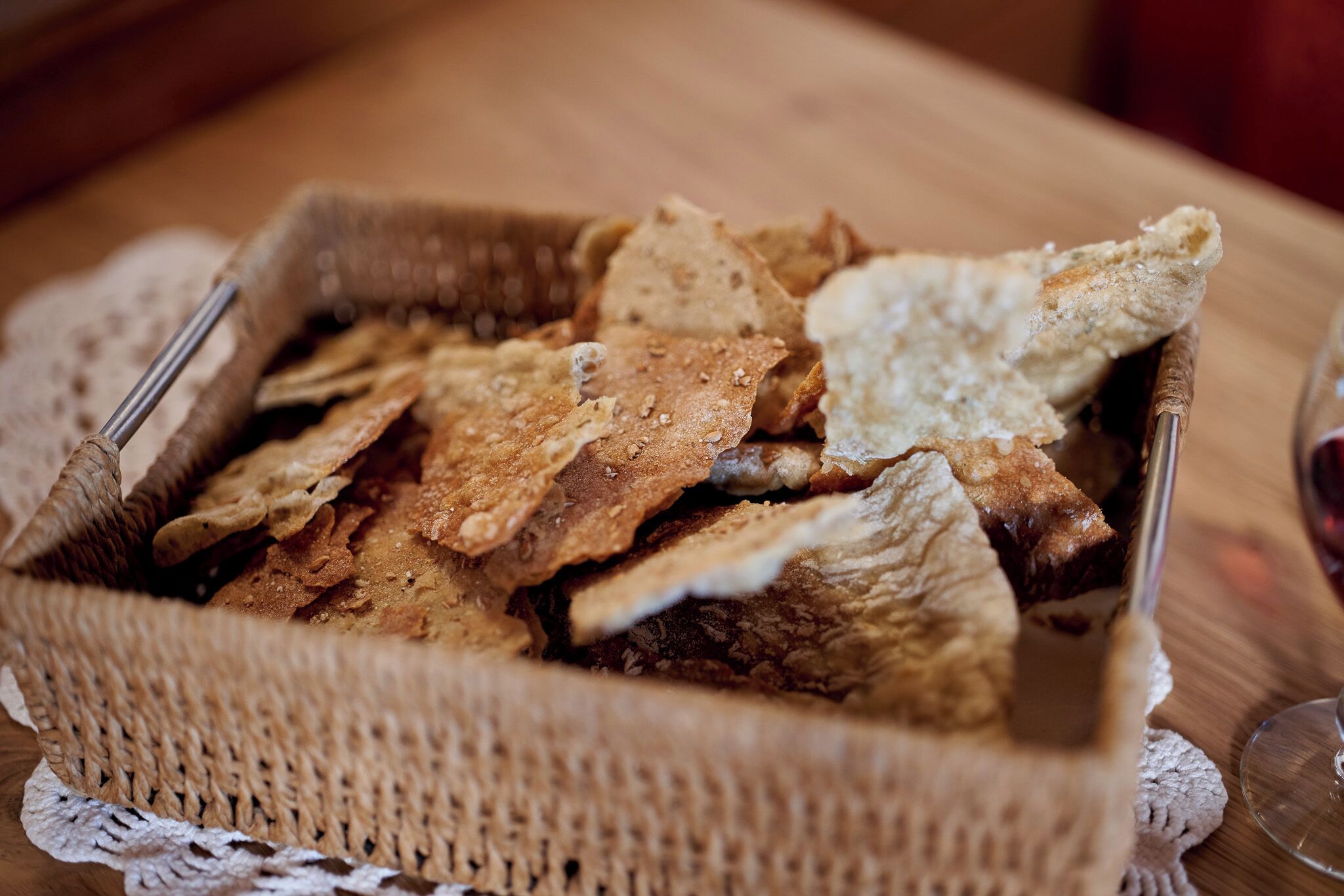 A basket of assorted crackers on a wooden table.