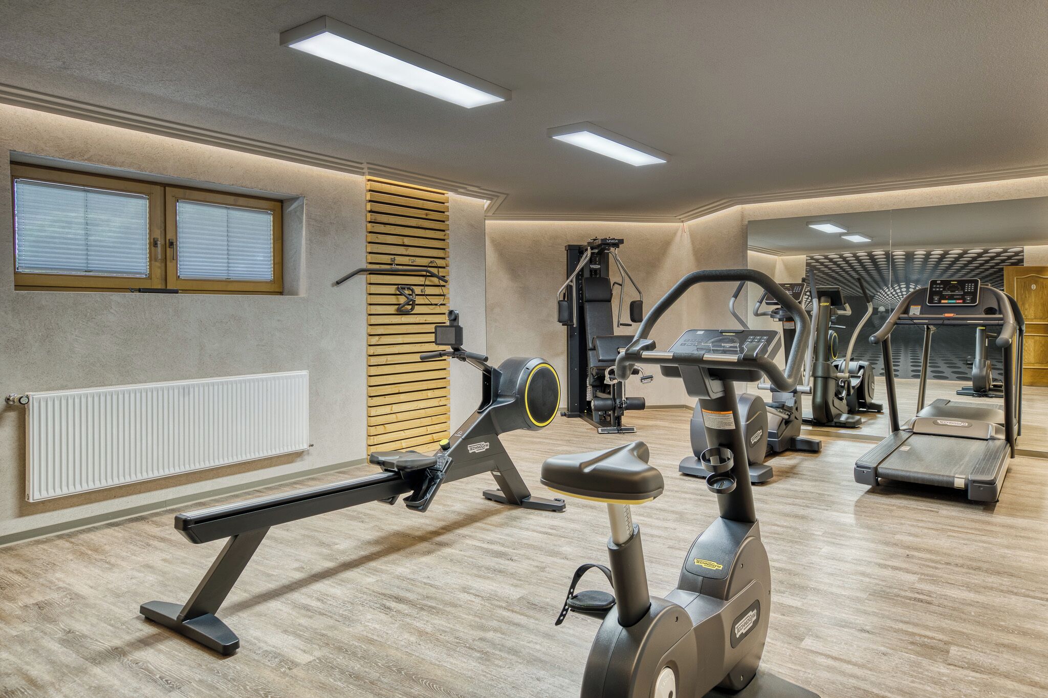 Een sportschool met trainingsapparatuur, een raam en een radiator.