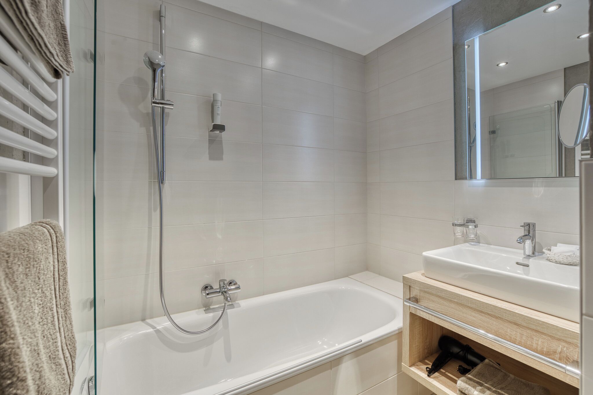 Un baño moderno con ducha envuelta en vidrio, bañera blanca y tocador con espejo.