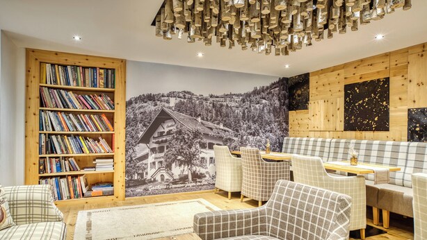 Ein gemütliches Zimmer mit Bücherregal, einer Couch und einem Essbereich mit Stühlen.