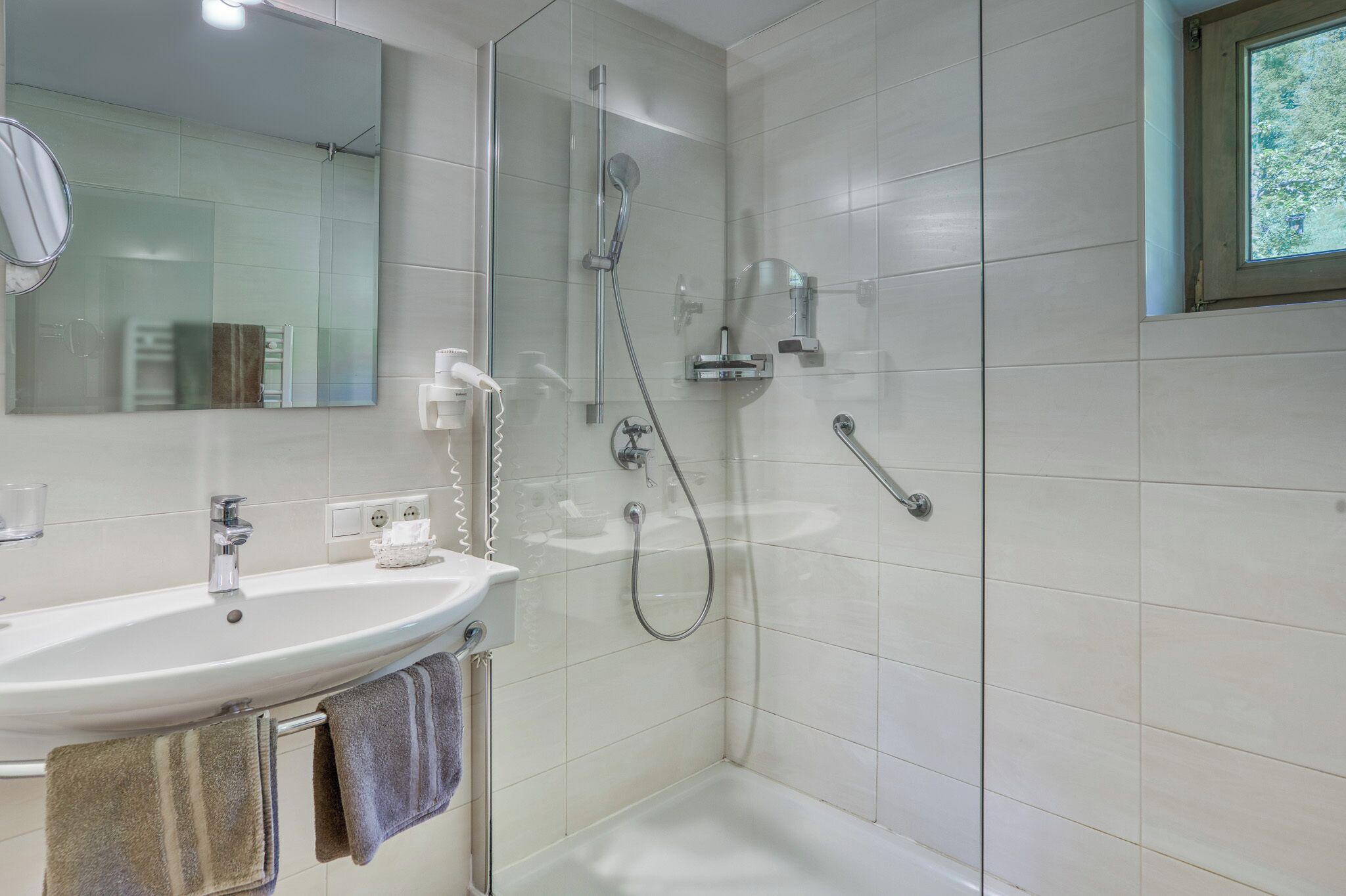 Ein modernes Badezimmer mit Waschbecken, Spiegel und Dusche.