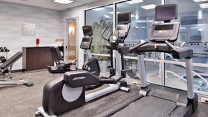 A fitness center with treadmills, exercise bikes, and a weight bench.