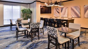 A conference room with a large table and chairs, a plant, and abstract wall art.