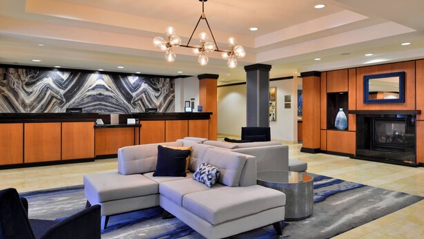 A modern lobby with a sectional sofa, a round coffee table, and a fireplace.