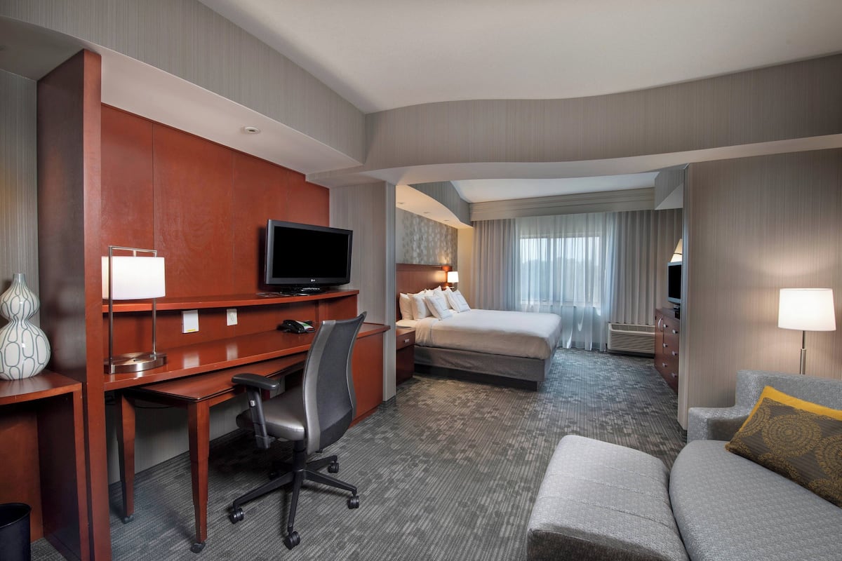 Een hotelkamer met een bed, een bureau met stoel, een televisie en een bank.