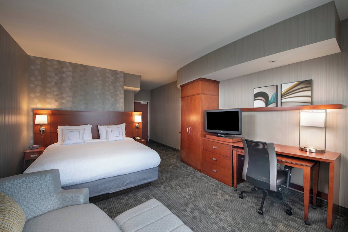 Een hotelkamer met een groot bed, een bureau met stoel, een televisie en een kledingkast.