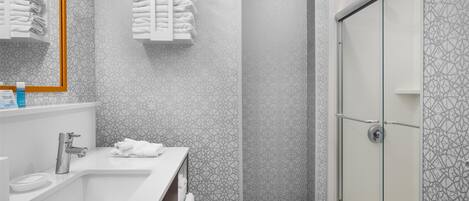 A modern bathroom with a large sink, a mirror, and a glass shower enclosure.
