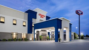 Un hotel Hampton Inn con fachada moderna, amplio acceso y exterior bien iluminado.