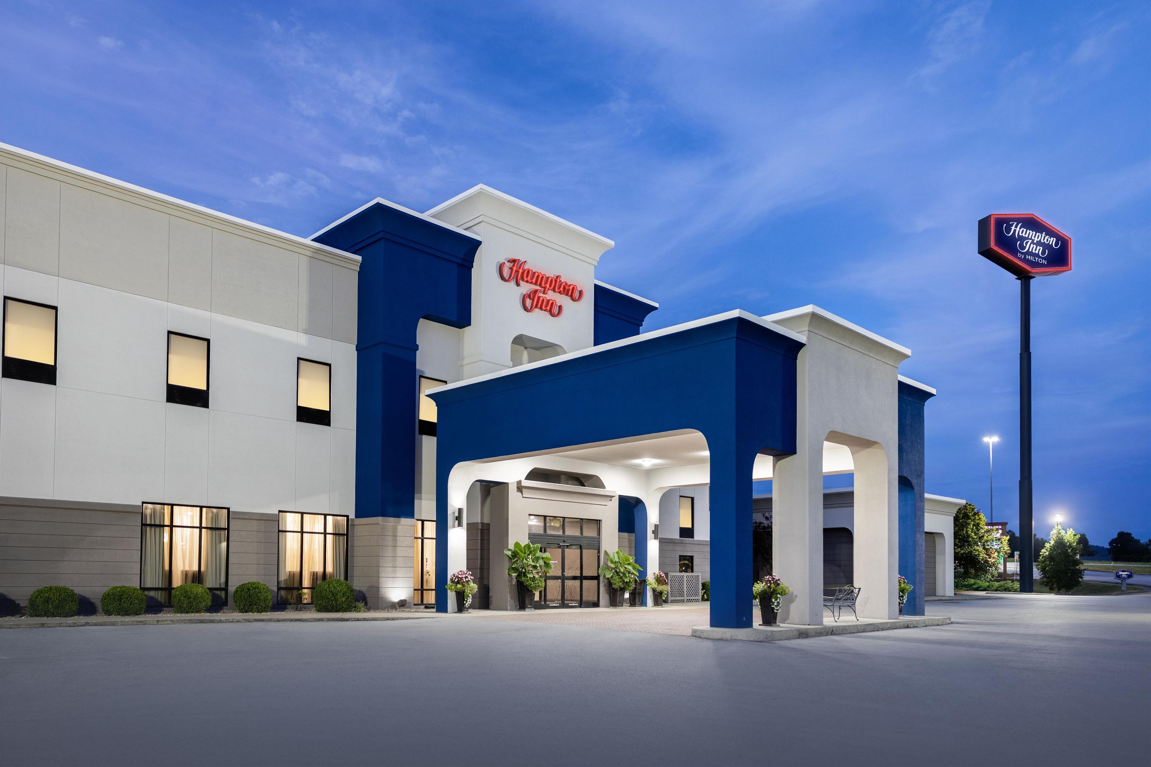 Een Hampton Inn hotel met een moderne gevel, een ruime entree en een goed verlichte buitenkant.