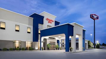 Een Hampton Inn hotel met een moderne gevel, een ruime entree en een goed verlichte buitenkant.