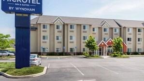 Un bâtiment de la chaîne Microtel Inn & Suites, avec un parking et un panneau indiquant les chambres de l’hôtel.