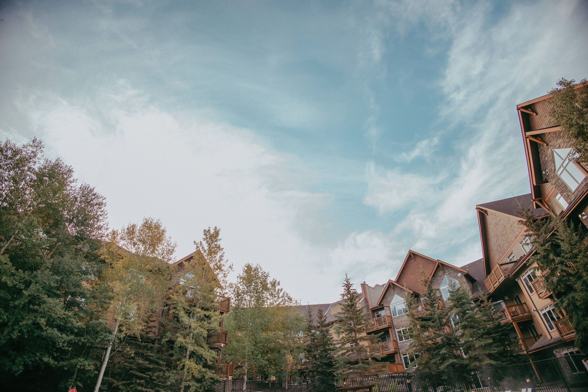 A multi-story building with a rustic architectural style, surrounded by trees.
