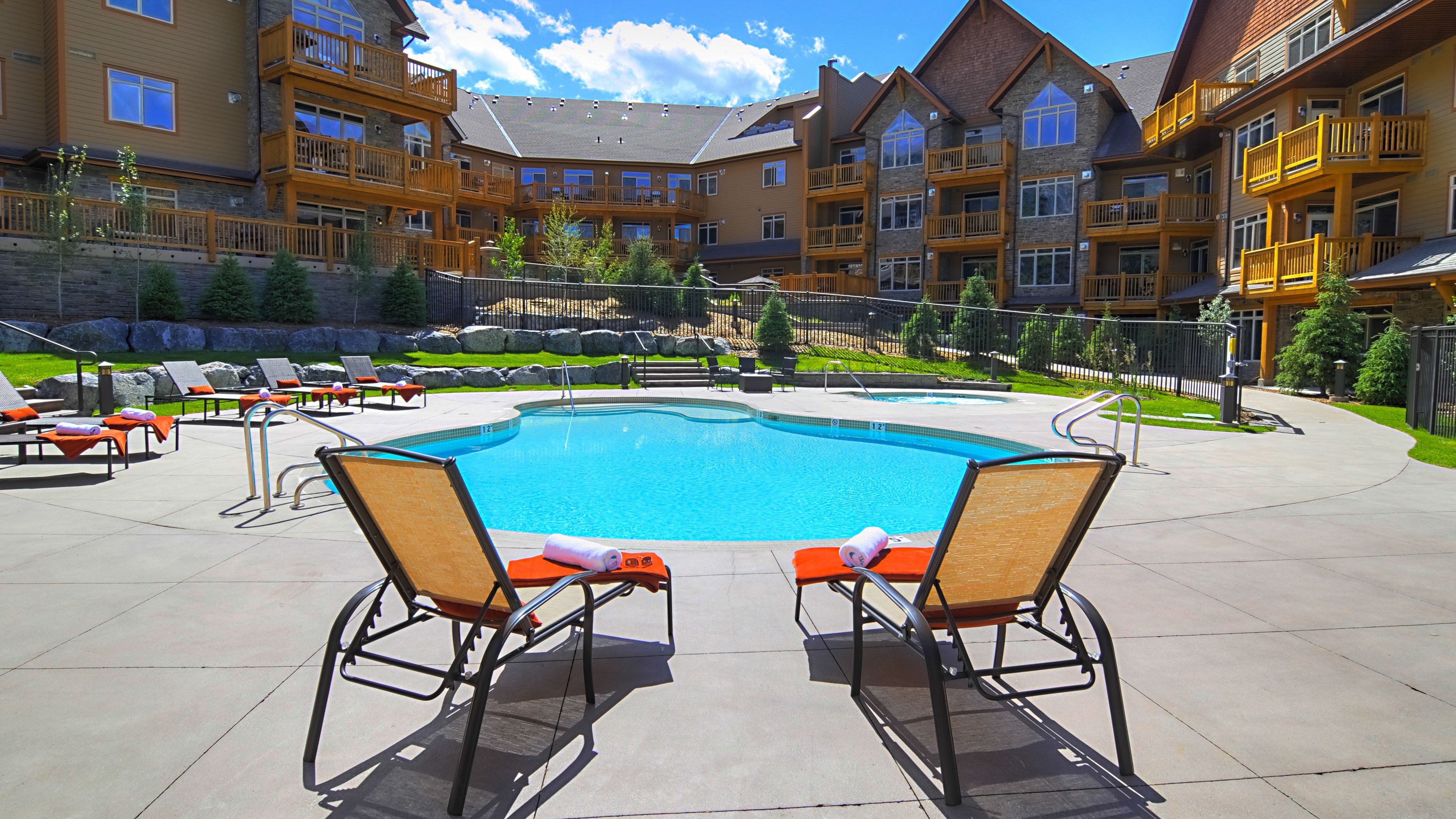 A pool area with lounge chairs and a clear blue pool.